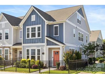 Charming two-story home featuring a black metal fence, blue siding, and a vibrant coral front door at 5008 Calvine Mill Way, Charlotte, NC 28205