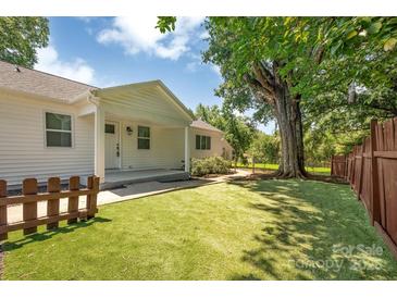 Inviting home exterior featuring a lush backyard, a covered patio, and mature trees at 6208 Karenstone Dr, Charlotte, NC 28215