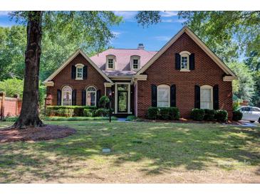 Charming brick home with manicured lawn, black shutters, and lush landscaping exudes curb appeal at 7014 Walton Heath Ln, Charlotte, NC 28277