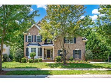 Charming brick two-story home with manicured lawn, mature trees, and dark shutters at 10104 Treetop Ln, Cornelius, NC 28031