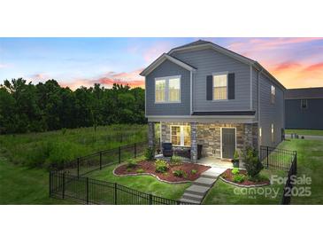 Charming home featuring stone accents, inviting front porch, landscaped yard, and a decorative black metal fence at 135 Orson Oaks Ln, Pineville, NC 28134