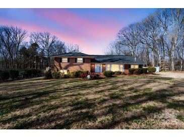 Charming brick home featuring manicured landscaping and a well-maintained lawn during a beautiful sunset at 220 Augusta Dr, Statesville, NC 28625