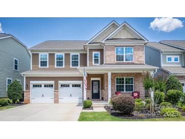 Charming two-story home featuring a brick and brown siding, a two-car garage and an inviting front porch at 134 Cherry Bark Dr, Mooresville, NC 28117