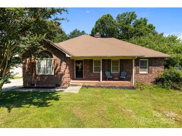 Charming brick ranch-style home featuring a well-manicured lawn and inviting front porch with seating at 160 Walking Horse Run, Stanley, NC 28164