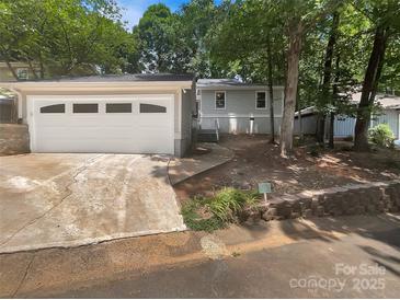 Charming one-story home featuring a detached garage, walkway, and inviting front yard, nestled amongst mature trees at 27 Quayside Ct, Clover, SC 29710