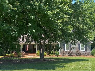 Charming home exterior with a front porch and beautifully landscaped front yard on a sunny day at 3210 Crow Row, Monroe, NC 28112