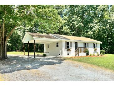Charming single-story home with a carport, featuring a brick facade and complemented by mature trees at 617 Rock Hill Church Rd, Matthews, NC 28104