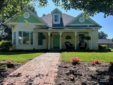 Charming yellow two-story home with a welcoming front porch, landscaped yard, and brick walkway at 743 S College Ave, Newton, NC 28658