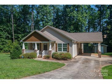 Charming single-Gathering home with covered porch, carport, and well-manicured lawn surrounded by lush greenery at 110 Leeper Ave, Belmont, NC 28012