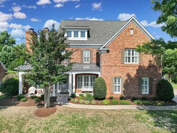 Beautiful brick home with manicured lawn, covered porch and a lush tree providing shade at 2909 Julian Glen Cir, Waxhaw, NC 28173