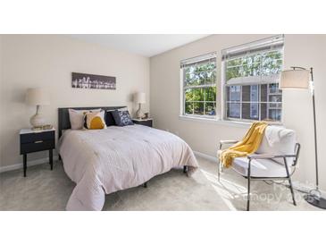 Bright bedroom features two large windows, modern decor, and soft carpet flooring at 1620 #K Arlyn Cir # K, Charlotte, NC 28213