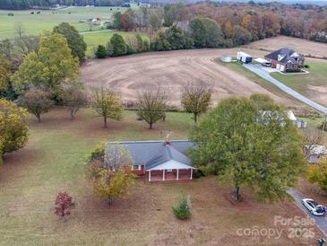 Expansive aerial view of the charming brick home and the surrounding acreage and fall foliage at 3113 Old Pageland Marshville Rd, Wingate, NC 28174