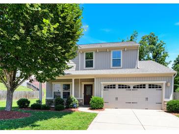 Charming home featuring gray siding, a two-car garage, manicured lawn, and beautiful mature trees at 7339 Dover Mill Sw Dr, Concord, NC 28025