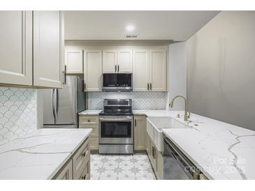Bright kitchen with stainless steel appliances, patterned backsplash, white cabinetry, and marble countertops at 795 Peninsula Dr, Davidson, NC 28036