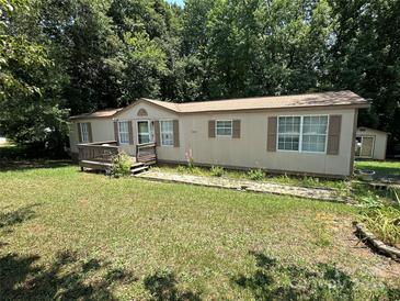 Tan single-story home with a small deck, brown shutters and a large front yard at 1355 Oak Breeze Dr, Mooresville, NC 28115