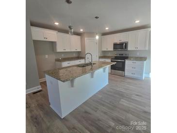 Bright kitchen with white cabinetry, stainless steel appliances, granite countertops, and a large center island with a sink at 200 N Kayla Dr, Salisbury, NC 28146