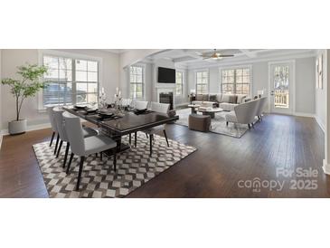 Open-concept living and dining area featuring hardwood floors, modern furniture, fireplace, and plenty of natural light at 704 Kenway Loop, Mooresville, NC 28117