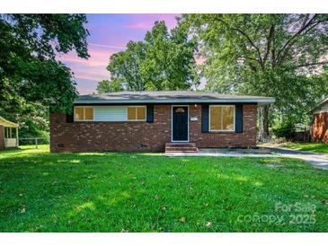 Charming one-story brick home with mature trees and well-maintained front lawn at 5323 Snow White Ln, Charlotte, NC 28213