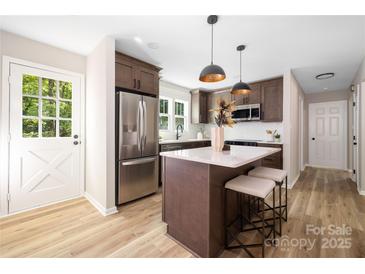 Modern kitchen featuring stainless steel appliances, an island with seating, and stylish pendant lighting at 7407 Limerick Dr, Charlotte, NC 28270
