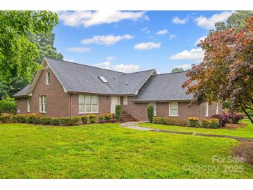Charming brick home featuring a well-manicured lawn, mature trees, and a classic architectural design at 36433 Azalea Cir, New London, NC 28127