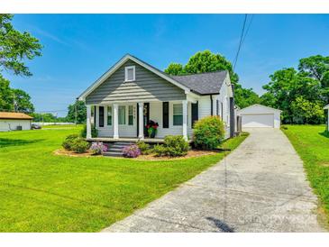 Charming home boasts a landscaped front yard and a detached garage with a long driveway on a sunny day at 903 Rhode Island Ave, Kannapolis, NC 28083