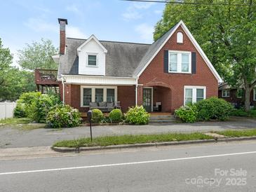 Charming brick home featuring an upstairs deck, a cozy front porch, and lovely garden landscaping at 1102 Lane St, Kannapolis, NC 28083