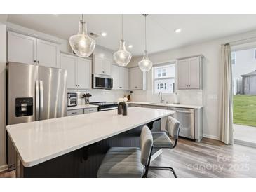 Bright kitchen features stainless steel appliances, shaker cabinets, and a large island with bar seating at 13323 Savaine St, Charlotte, NC 28278