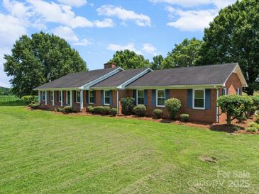 Charming brick home with a lush green lawn, blue shutters and mature landscaping at 1904 Old Peachland Rd, Marshville, NC 28103