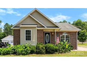 Charming brick home with a well-manicured lawn, complemented by lush landscaping around the front entrance at 400 N Main Gq St, Granite Quarry, NC 28146