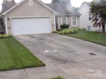 Tan single-story home with two-car garage and well-maintained landscaping at 569 River View Dr, Lowell, NC 28098