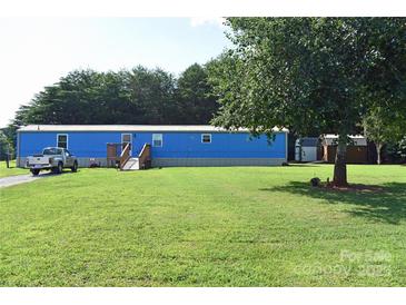 Blue single-story home features well-maintained lawn, sheds, and natural tree coverage at 589 Owls Den Rd, Lincolnton, NC 28092