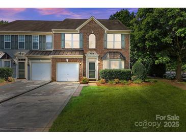 Charming brick townhome featuring an attached garage, well-maintained lawn, and inviting curb appeal at 157 Talbert Town Loop, Mooresville, NC 28117