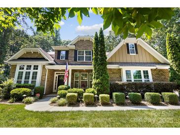 Charming brick home featuring manicured landscaping, an American flag, and a welcoming entrance at 7327 Snowbird Ct, Mint Hill, NC 28227
