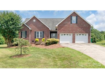 Charming red brick home boasts a manicured lawn, mature landscaping, and an attached two-car garage at 773 Hathcock Glen Dr, Oakboro, NC 28129