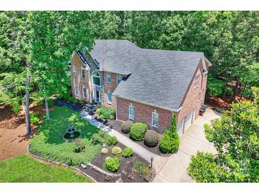 Impressive brick home with manicured landscaping, fountain, and three-car garage nestled in lush greenery at 19900 Stough Farm Rd, Cornelius, NC 28031