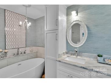 Bright bathroom features a soaking tub, patterned tile accent wall, and white vanity with a decorative mirror at 666 Tryon Pl, Gastonia, NC 28054