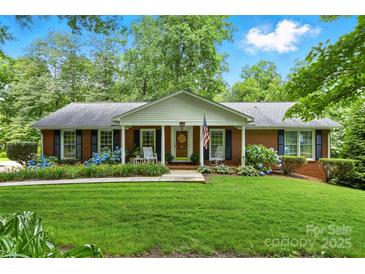 Charming single-story brick home featuring a well-manicured lawn, blooming hydrangeas, and a welcoming front porch at 701 4Th Ne Ave, Conover, NC 28613