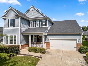 Charming two-story home featuring gray siding, black shutters, and a well-manicured front yard with inviting front porch at 12415 Es Draper Dr, Huntersville, NC 28078