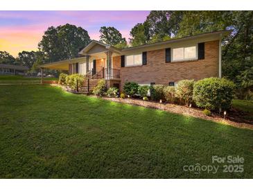 Charming brick home with a well-manicured lawn, front porch, and professionally landscaped front yard at 143 Bostian Lake Rd, Statesville, NC 28677
