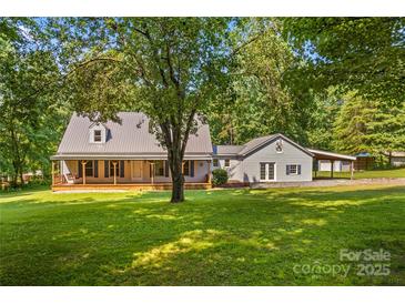 Charming home featuring a covered porch, metal roof, light siding, and lush landscaping at 265 River Run Rd, Statesville, NC 28625