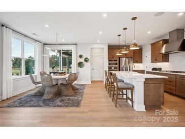 Open-concept kitchen with stainless appliances, island with breakfast bar, and adjacent dining area, perfect for modern living at 327 Ardmore Dr, Belmont, NC 28012