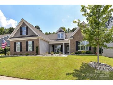 Charming brick home featuring a well-manicured lawn, inviting curb appeal, and decorative stone landscaping at 5129 Devonshire Rd, Denver, NC 28037