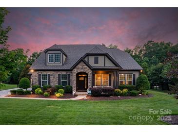 Charming stone and siding home with well-manicured landscaping and a welcoming front entrance at twilight at 2009 Freeport Dr, Indian Trail, NC 28079