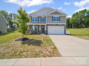 Charming two-story home boasts stone accents, gray siding, well-manicured lawn, and a two car garage at 404 Saddlebred Ln, Locust, NC 28097