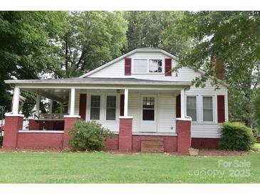 Charming home featuring a covered porch, brick accents, and a well-manicured lawn at 4143 E Maiden Rd, Maiden, NC 28650
