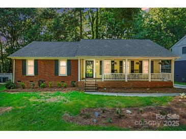 Charming single-story home with a welcoming front porch, brick accents, and lush landscaping at 9334 New Towne Dr, Matthews, NC 28105