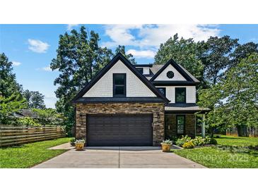 Charming two-story home with stone accents, a black roof, and a well-manicured lawn at 5511 Milhaven Ln, Charlotte, NC 28269