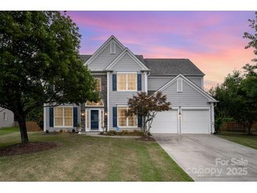 Charming two-story home featuring stone accents, blue shutters, and a well-manicured lawn at twilight at 7623 Rathburn Ln, Charlotte, NC 28277