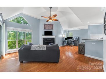 Bright living room with vaulted ceiling, fireplace, hardwood floors, and a large window at 2510 Cranbrook Ln, Charlotte, NC 28207
