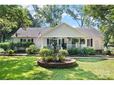 Charming single-story home with well-manicured lawn, fountain, and inviting front porch at 4534 Pebblebrook Sw Cir, Concord, NC 28027